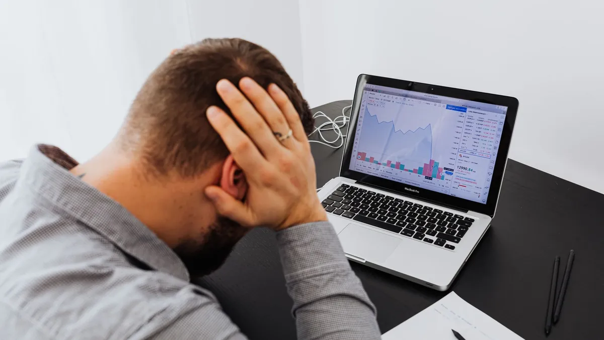 A person at a desk looking at declining charts on a laptop