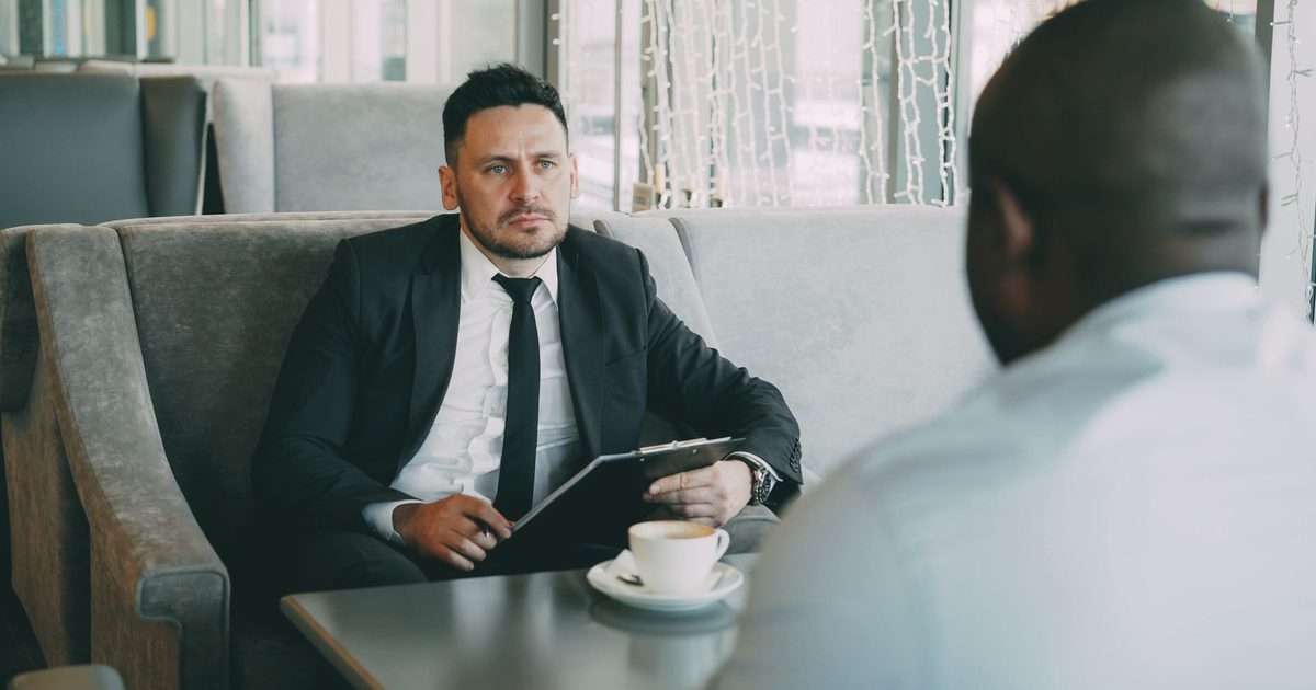 Two people in a serious conversation over coffee at a café table
