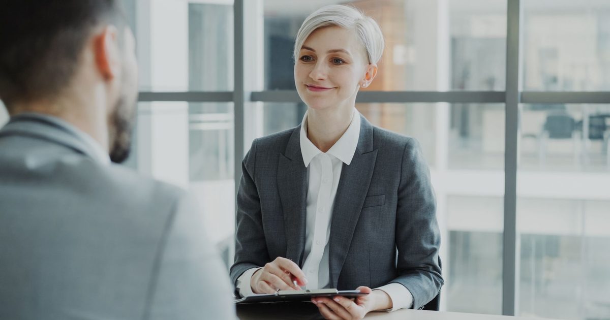 Two people in an office during a job interview, one taking notes