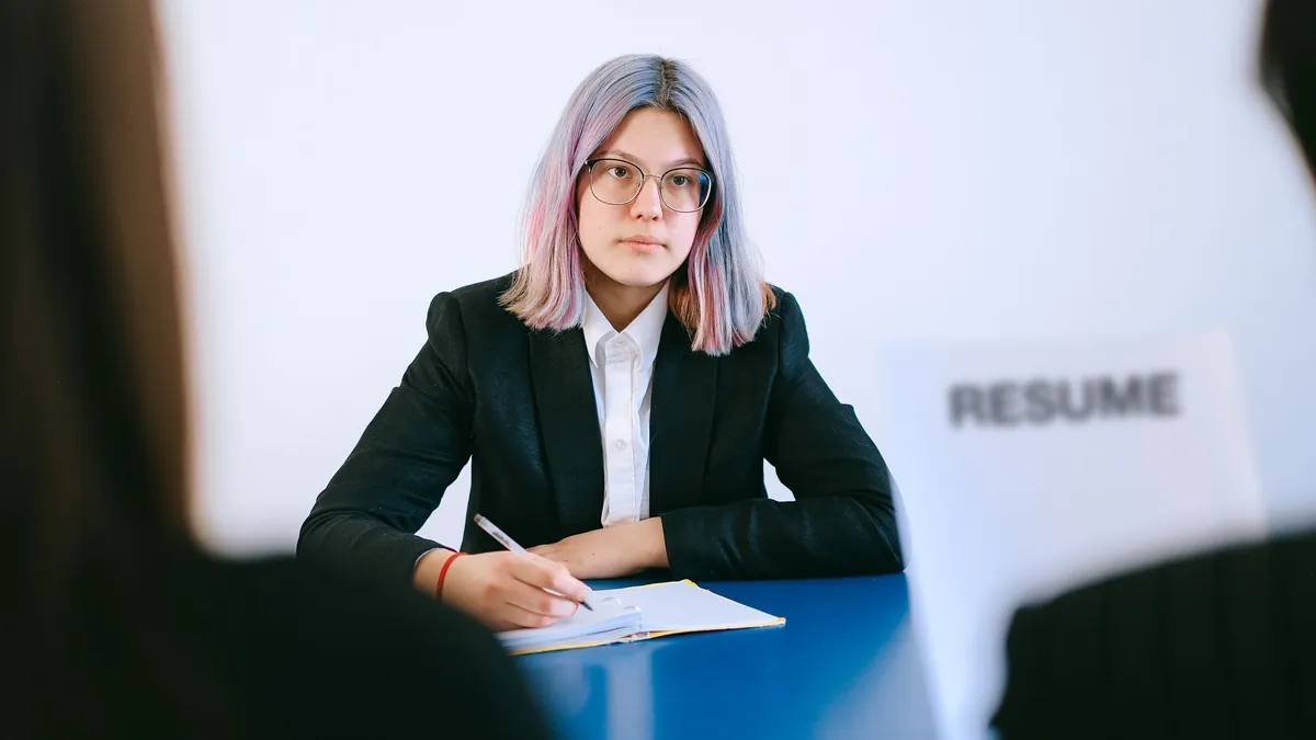 A person in a suit taking notes during an interview