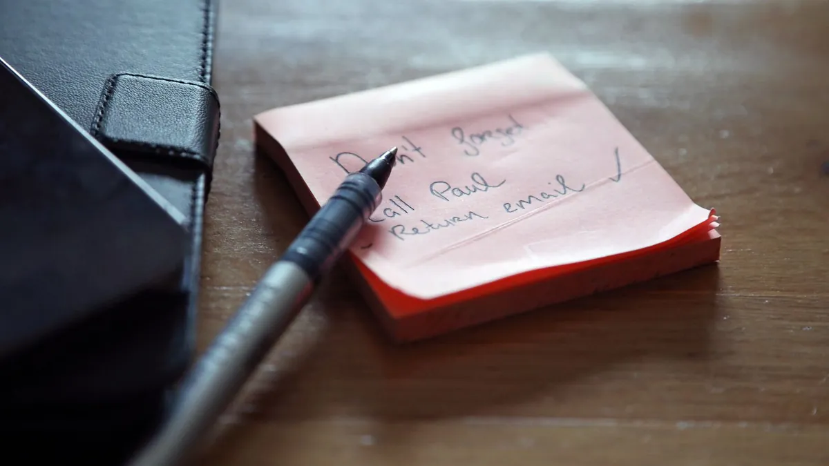 Sticky notes with a handwritten to-do list and a pen on a desk