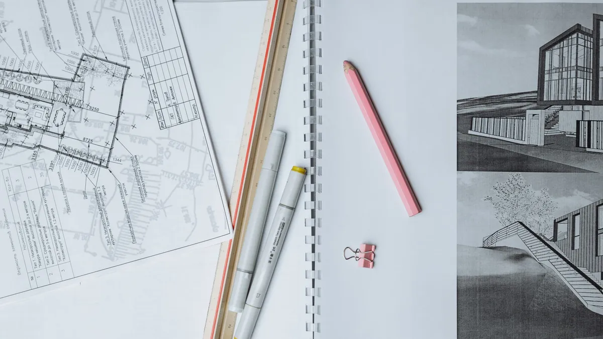 Architectural blueprints, a ruler and drawing tools laid out on a desk