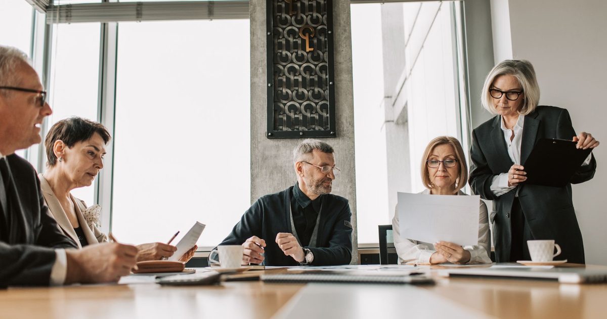 People around a meeting-room table reviewing documents together