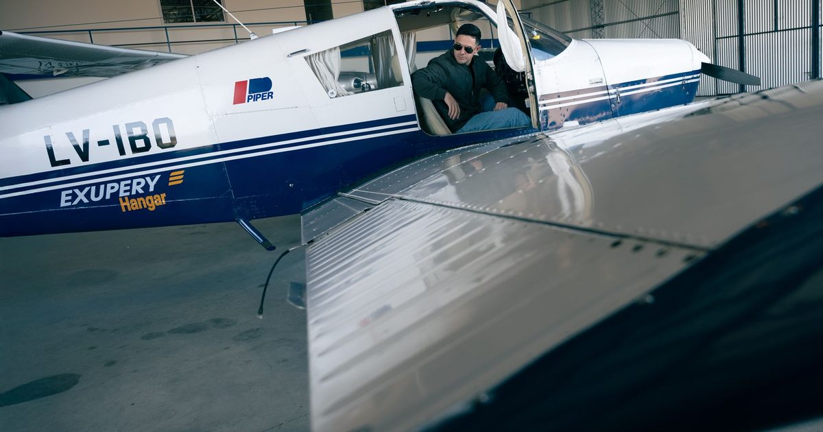 A pilot seated in a small aircraft inside a hangar before departure